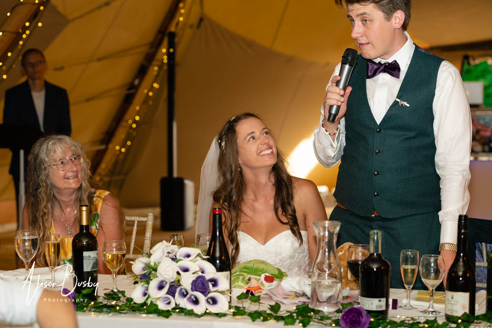 Bride and groom enjoy speeches at Oxfordshire tipi wedding. Dovecote Events.