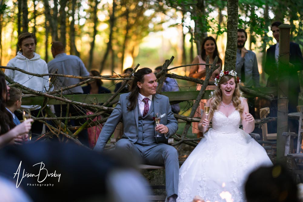 Buckinghamshire woodland wedding photographer. Wedding party around firepit at sunset. Endeavour Woodland Weddings.