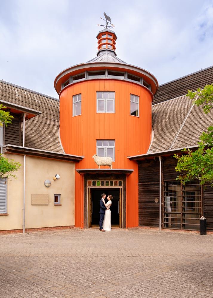 Bride and groom face each other in doorway of Sheepdrove Organic Farm at Berkshire wedding by professional photographer.
