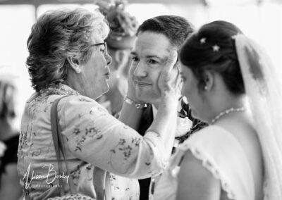 Relative kissing groom in lineup at Milton Hill House wedding Oxfordshire