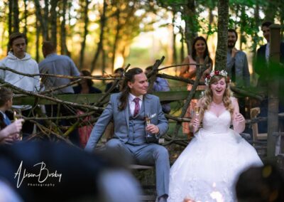 Buckinghamshire woodland wedding. Bride and groom with guests around fire pit at Endeavour woodland weddings.