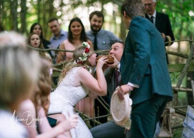 Buckinghamshire woodland wedding. Bride and groom with guests around fire pit at Endeavour woodland weddings.