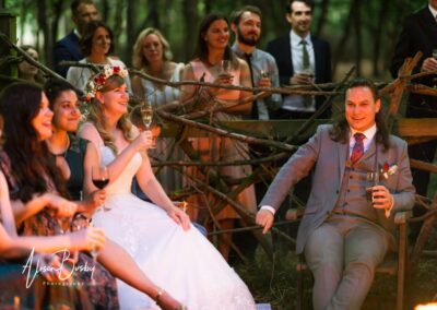 Buckinghamshire woodland wedding. Bride and groom with guests around fire pit at Endeavour woodland weddings.