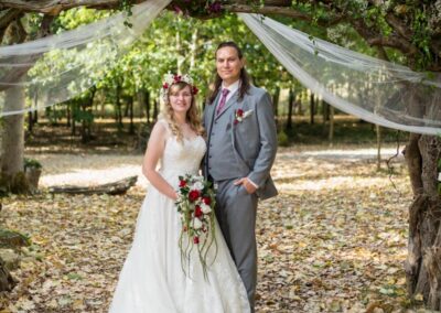 Buckinghamshire woodland weddings. Bride and groom under arch at Endeavour woodland weddings.