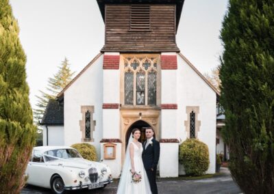 Bride and groom with white jaguar wedding car outside church in Chesham Bois Buckinghamshire