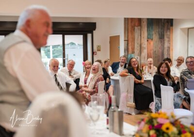 Older Couple wedding photographs. Guests laughing during groom's speech.