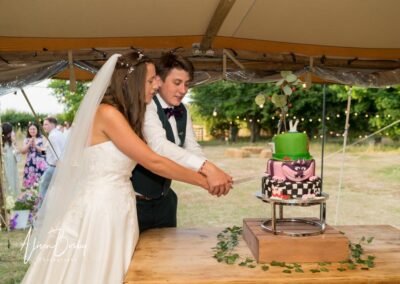 Oxfordshire tipi wedding at Dovecote Events. Bride and groom cut wedding cake.