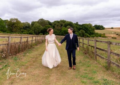 Sheepdrove Organic Farm in Berkshire. Bride and groom walk from Lake.