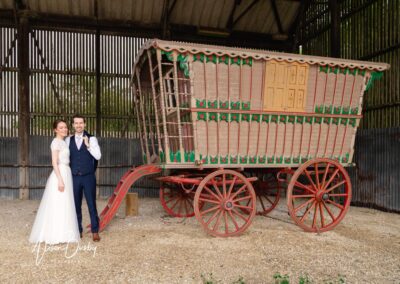 Sheepdrove Organic Farm in Berkshire. Bride and groom next to romany caravan.