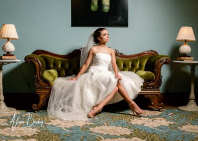 Wedding photography styles. Portrait of a bride seated on a green sofa.