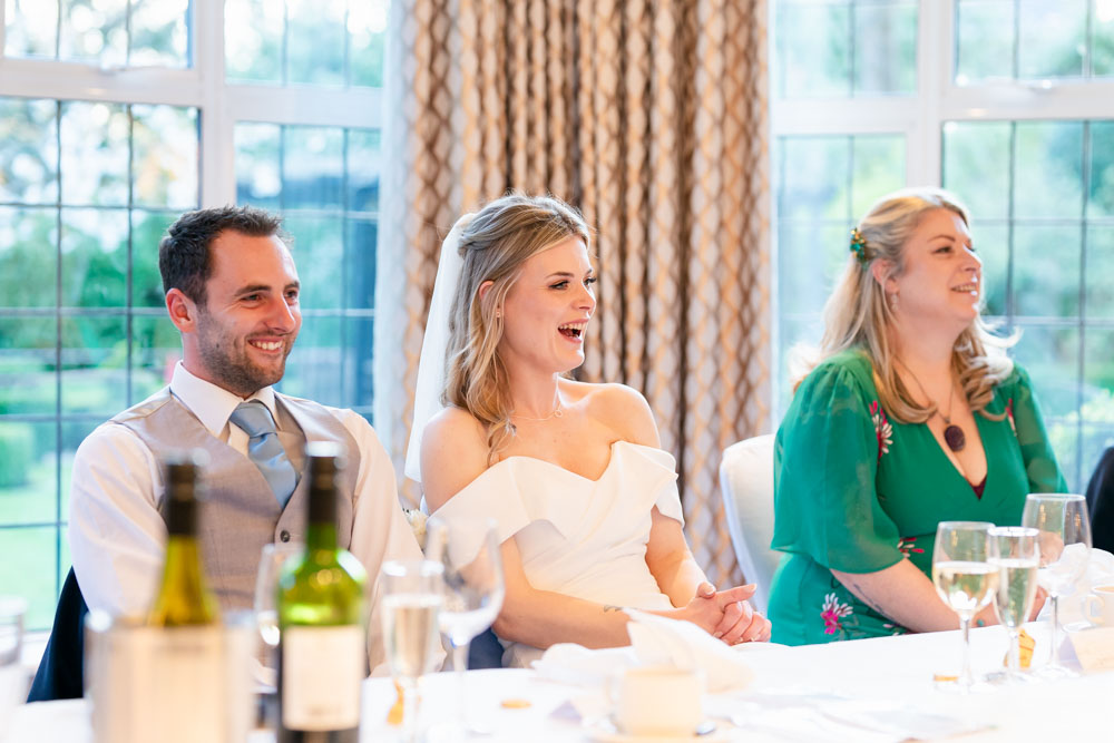 Bride and groom laughing during speeches at the Bull Hotel in Gerrards Cross