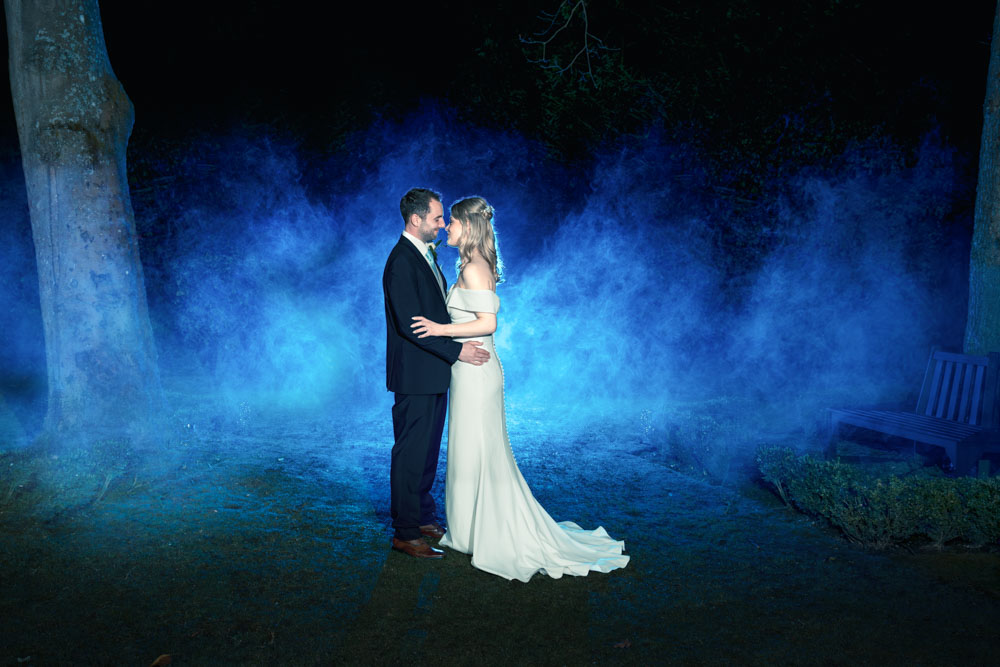 Bride and groom with blue smoke at Bull Hotel Gerrards Cross. Night wedding photo.