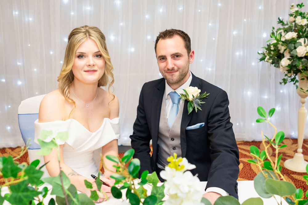 Bride and groom signing register at the Bull Hotel in Gerrards Cross