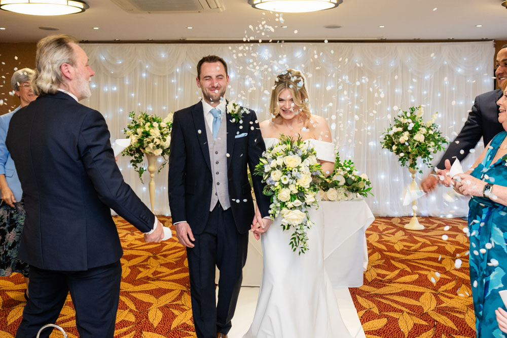 Guests throw confetti at the the bride and groom after ceremony at the Bull Hotel in Gerrards Cross