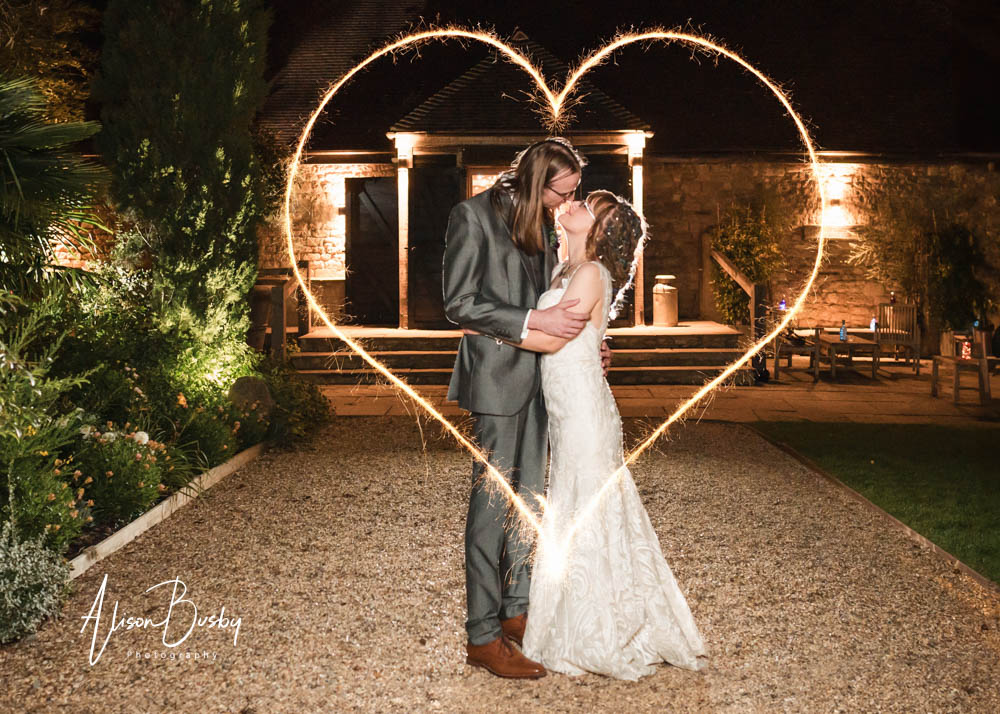 ight painting wedding photos. Bride and groom with sparkler heart at Notley Tythe Barn in Buckinghamshire.