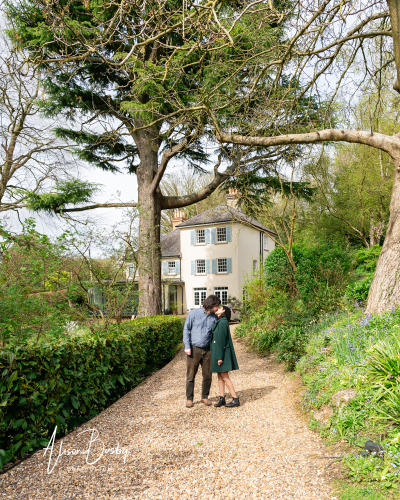 Amersham engagement photos. Young couple kiss on the drive of a stunning property in Buckinghamshire.