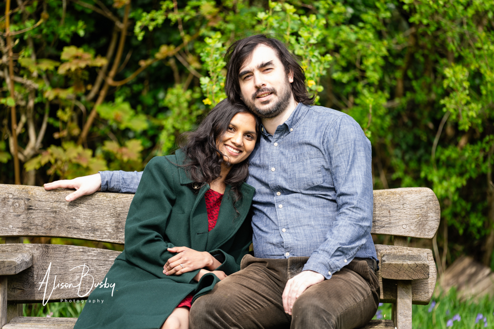Amersham engagement photos. Young couple seated on bench in Buckinghamshire garden