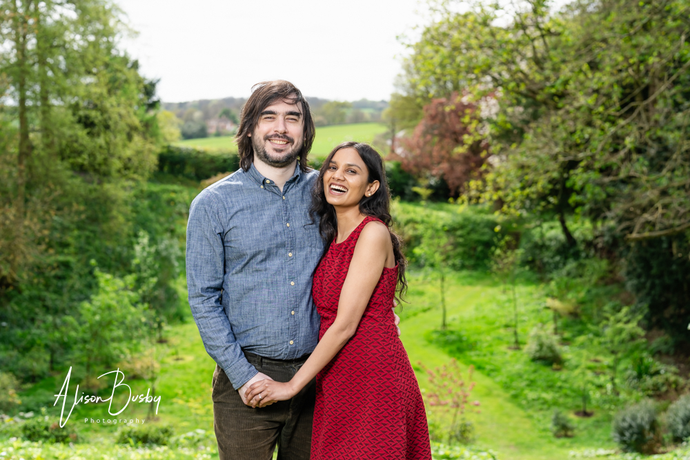 Amersham engagement photos. Young couple laughing with stunning backdrop in Buckinghamshire garden