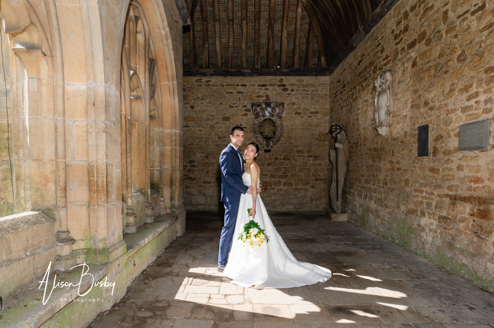 Wedding photos Oxford. Bride and groom stand in pool of sunlight streaming through Cloisters at New College Oxford