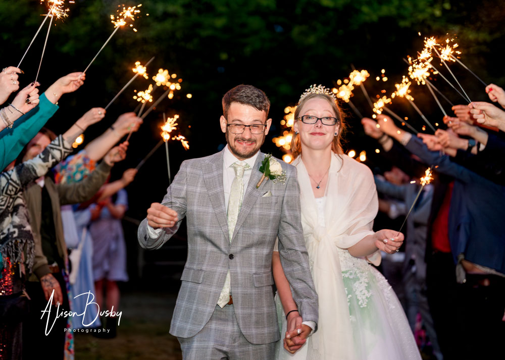 Night time wedding photo with sparklers. Bride and groom in sparkler exit.