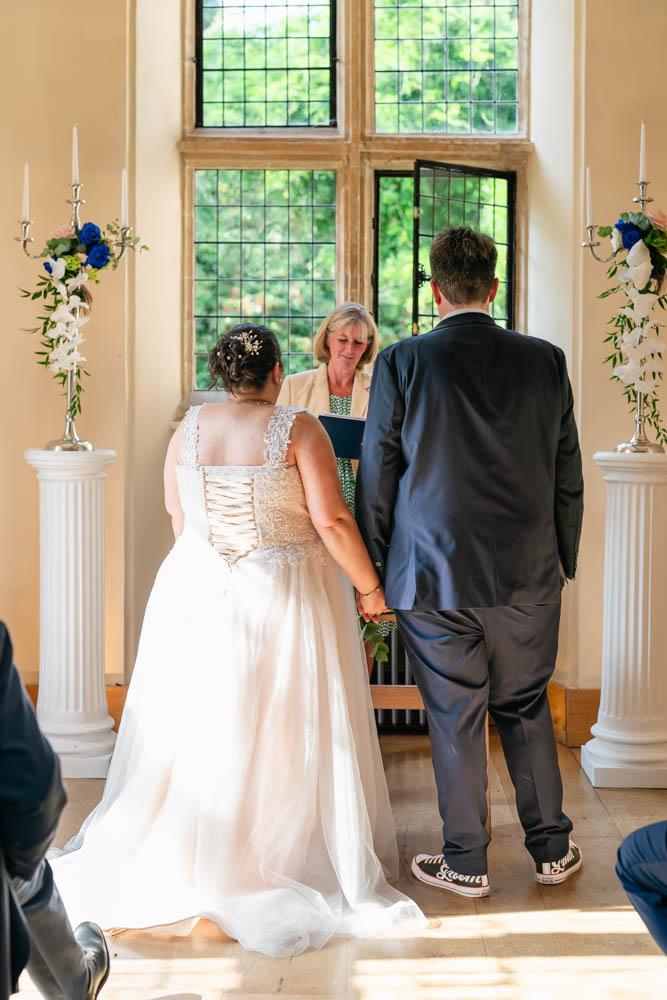 Notley Abbey wedding photographer. Bride and groom hold hands during ceremony in Abbot's Hall