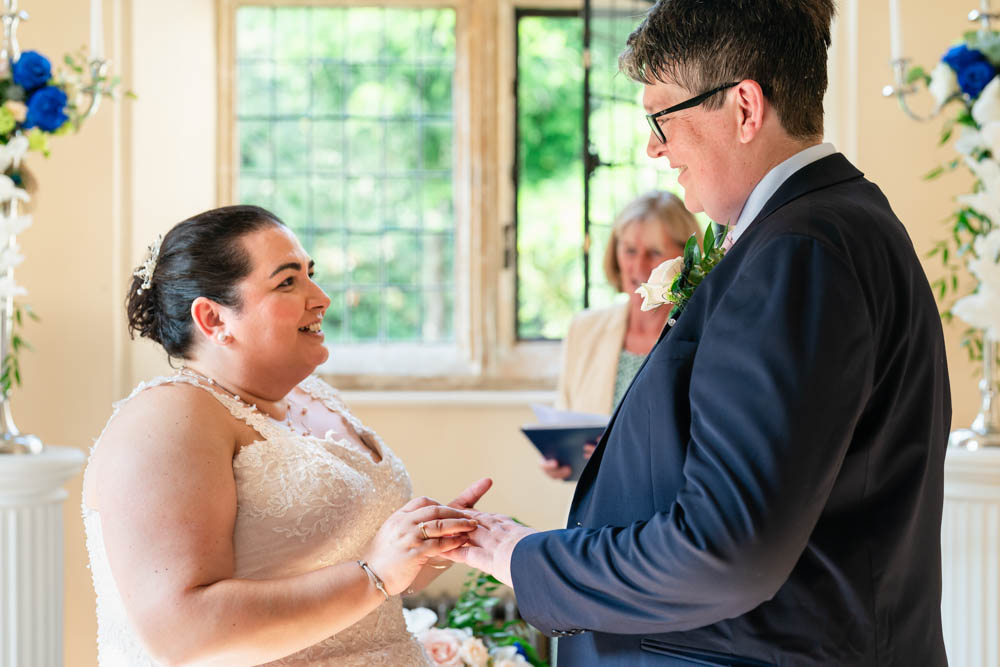 Notley Abbey wedding photographer. Bride and groom exchange rings in Abbot's Hall