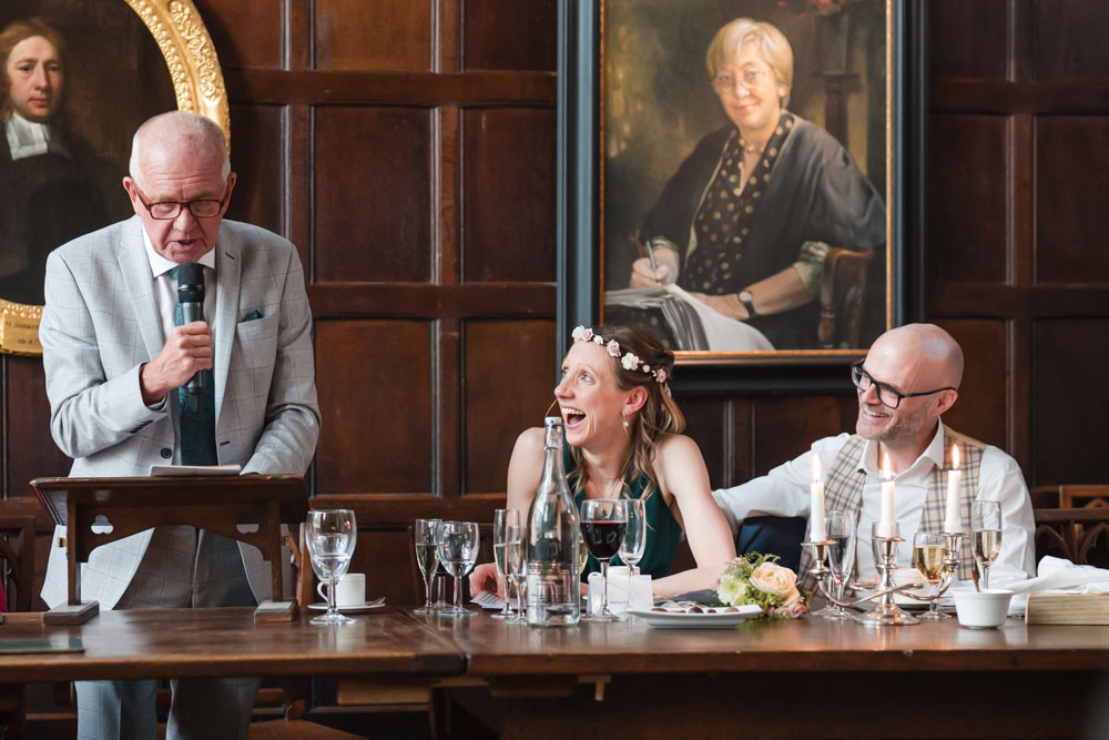 Bride and groom laughing during speeches at Exeter College wedding