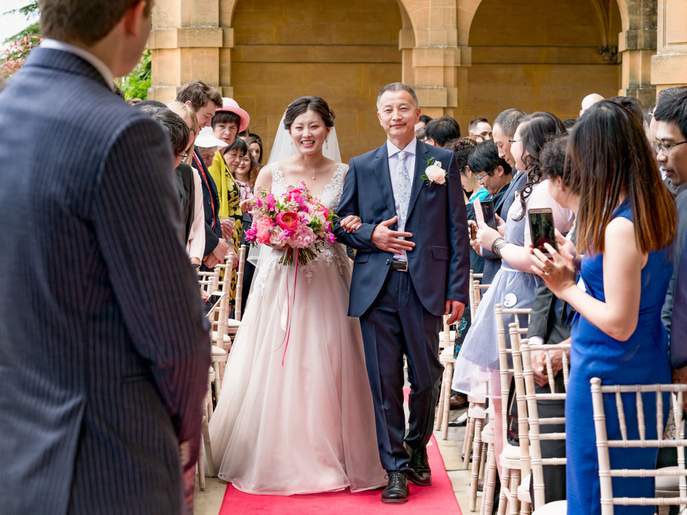 Wedding photography Oxfordshire. Bride arrives for outdoor wedding ceremony at Eynsham Hall