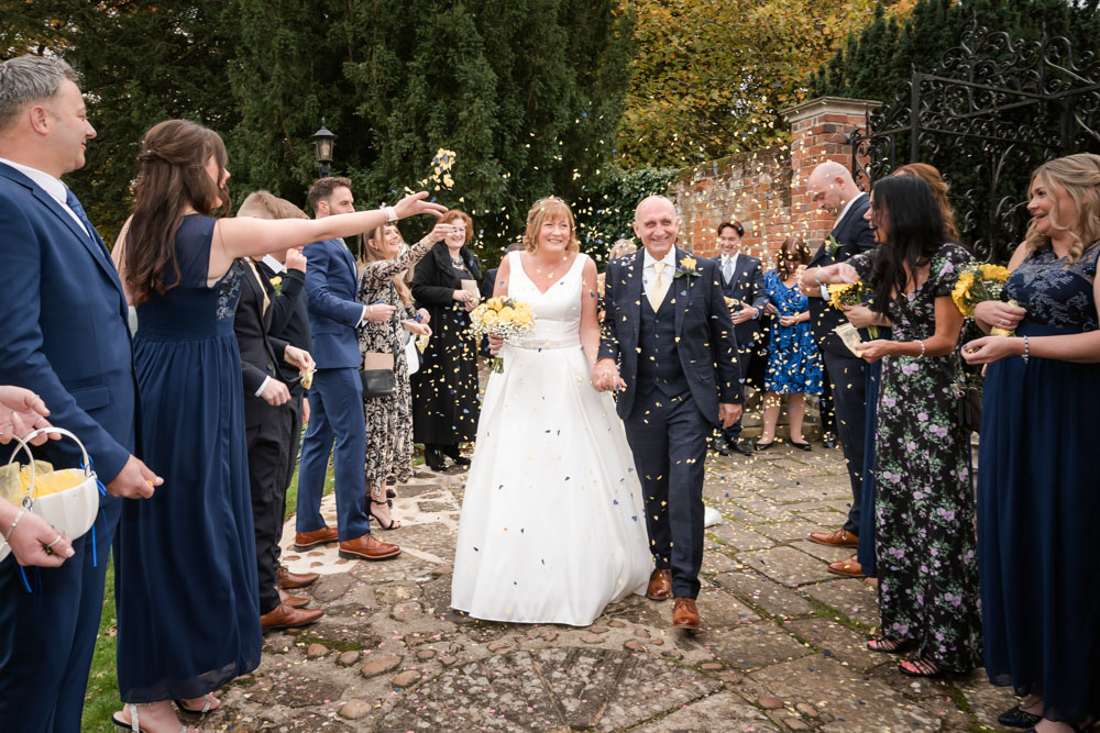 Wedding photos Coseners House. Bride and groom walk through confetti tunnel in garden of hotel.