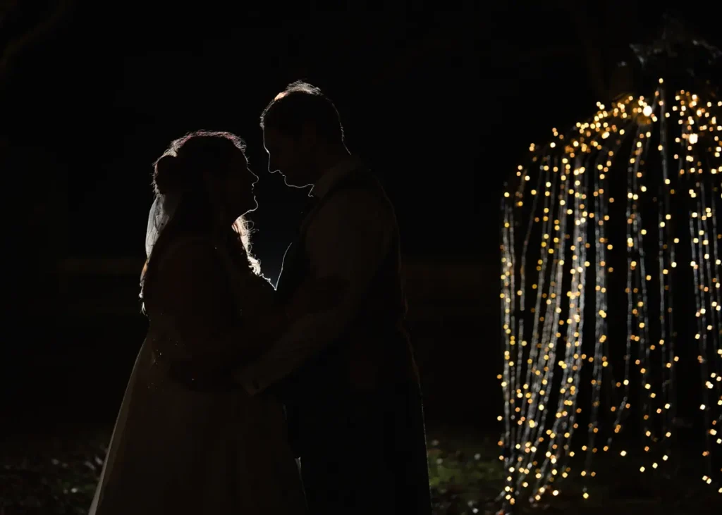 Nighttime wedding photo of bride and groom at the Garden House Venue in Steventon, Oxfordshire with background fairy lights.