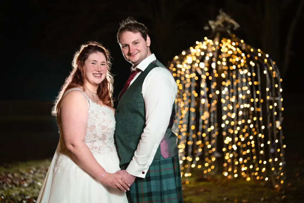Nighttime wedding photo of bride and groom at the Garden House Venue in Steventon, Oxfordshire with the background bokeh of fairy lights on a gazebo.