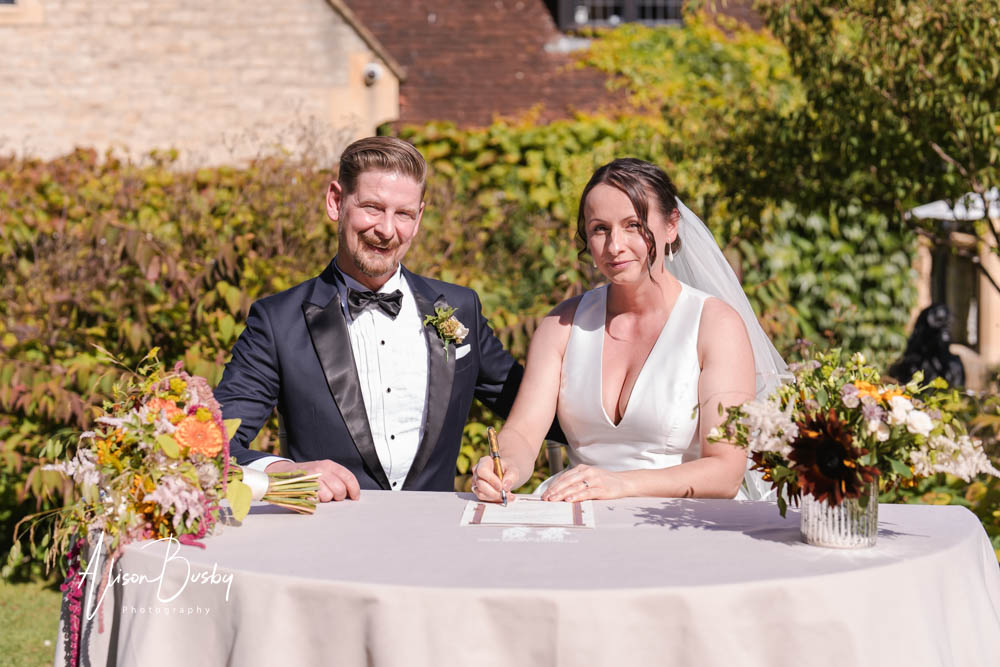 Bride and groom registry signing after outdoor wedding ceremony at Le Manoir aux Quat'Saisons. Photo by Alison Busby