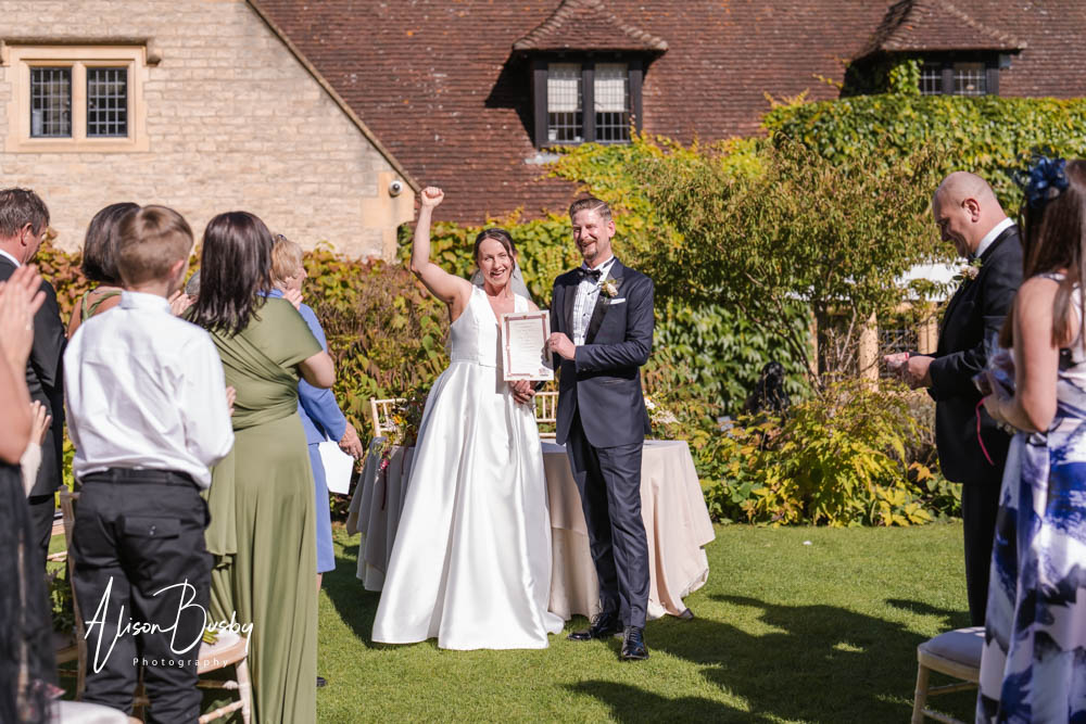 Bride celebrating after outdoor wedding ceremony at Le Manoir aux Quat'Saisons. Photo by Alison Busby