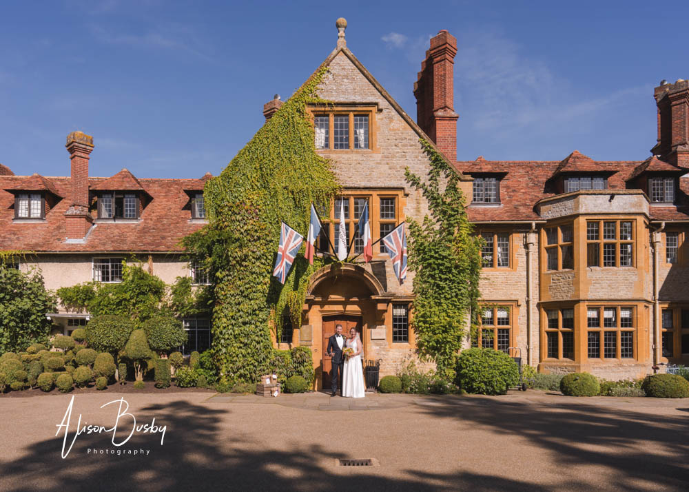 Newlywed at entrance to Le Manoir aux Quat'Saisons by Le Manoir wedding photographer alison busby
