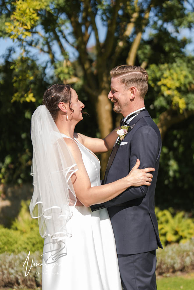 Le Manoir wedding photographer with bride and groom laughing in gardens of Le Manoir aux Quat'Saisons.