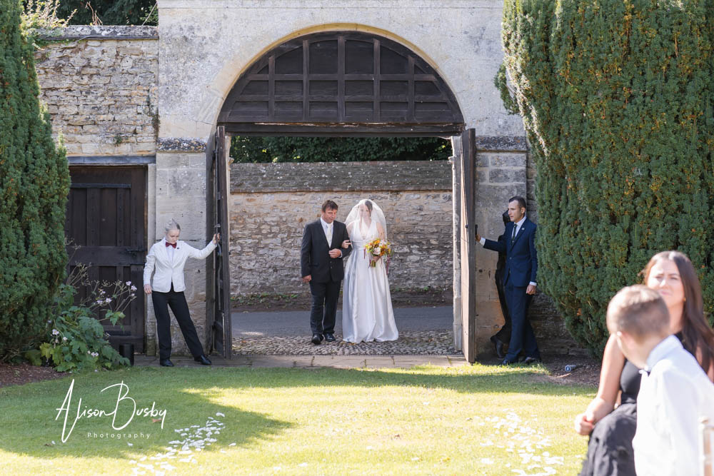 Natural wedding photography at Le Manoir aux Quat'Saisons in Oxfordshire. Bride arrives for an outdoor wedding ceremony.