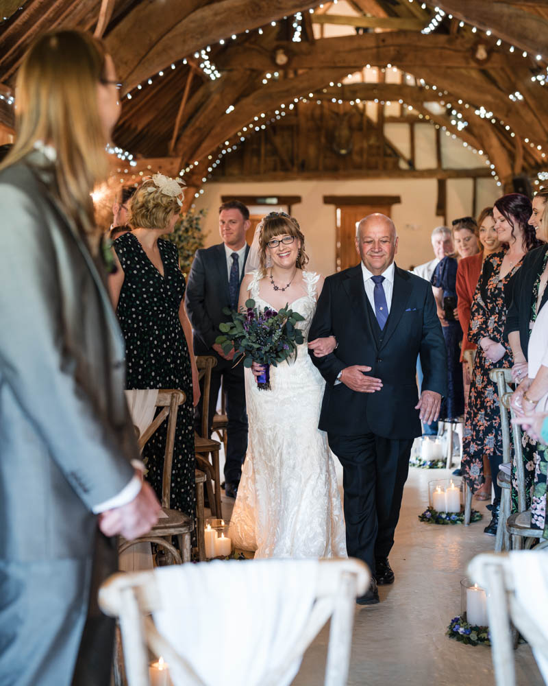 Bride walks up the aisle at Notley Tythe Barn wedding in Long Crendon, Buckinghamshire.