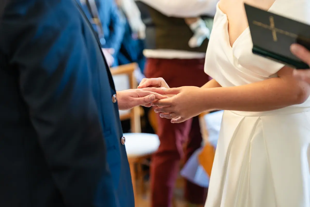 Bride and groom exchange rings at Farnham Castle wedding.