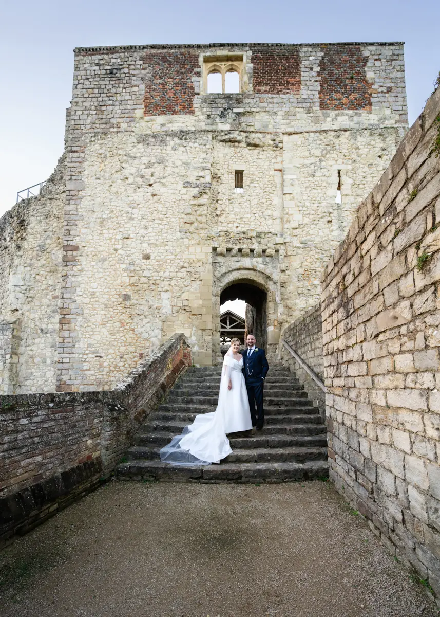 Bride and groom on steps at entrance of castle keep at their Farnham Castle wedding.