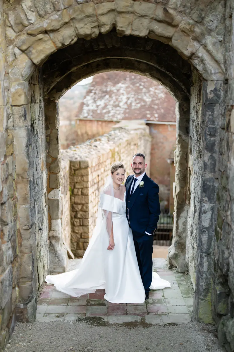 Bride and groom on steps of castle keep at their Farnham Castle wedding.