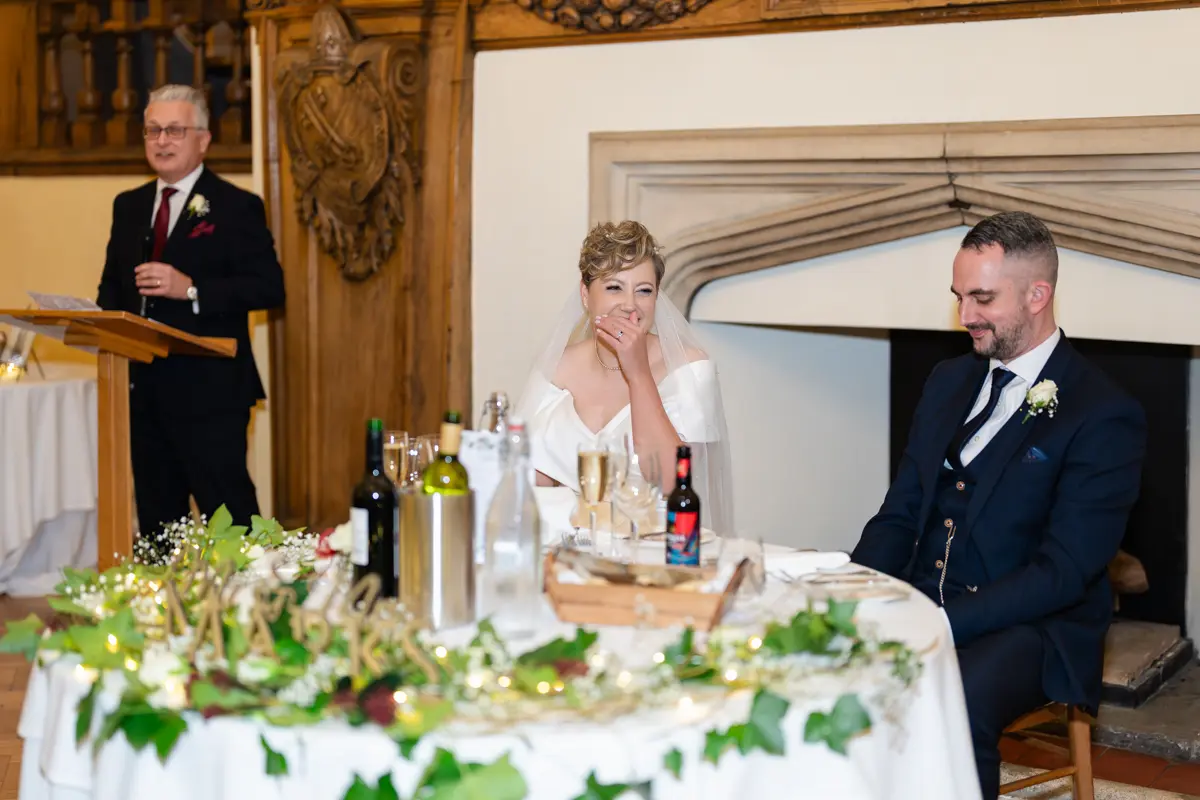 Bride laughing during father's speech at Farnham Castle wedding.