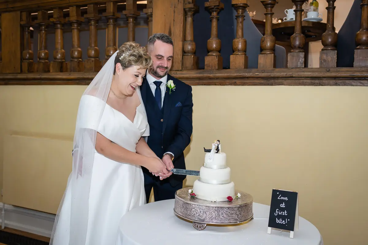 Bride and groom cutting the cake at their Farnham Castle wedding.