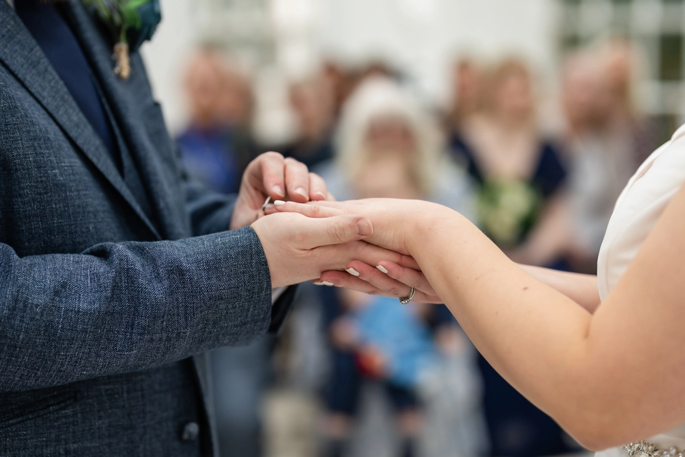 Bride and groom exchanging rings during ceremony in conservatory. Hunton Park wedding photographer.