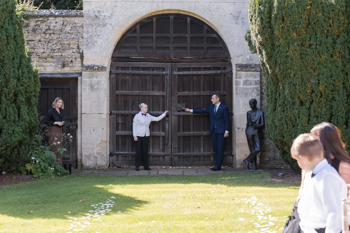 Staff open gate for bride's arrival for outdoor ceremony at Le Manoir wedding.