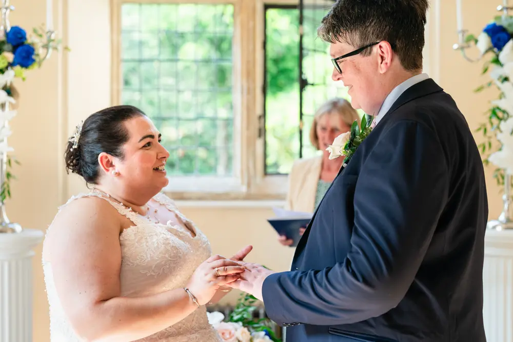 Notley Abbey Wedding photographer. Bride and groom exchange rings during ceremony.