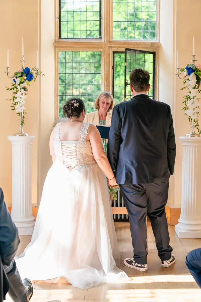 Notley Abbey Wedding photographer. Bride and groom hold hands during ceremony.