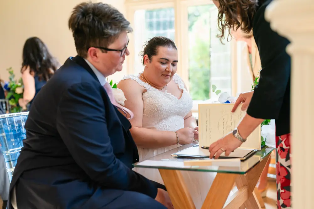 Notley Abbey Wedding photographer. Bride and groom signing the register.