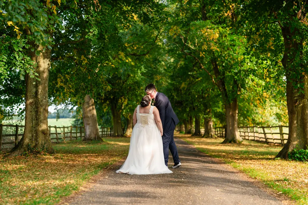 Notley Abbey Wedding photographer. Bride and groom kiss on avenue of trees, created by Vivien Leigh.