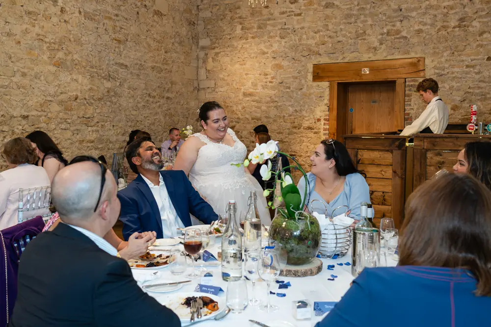 Notley Abbey Wedding photographer. Bride laughing with guests in Monk's refectory.