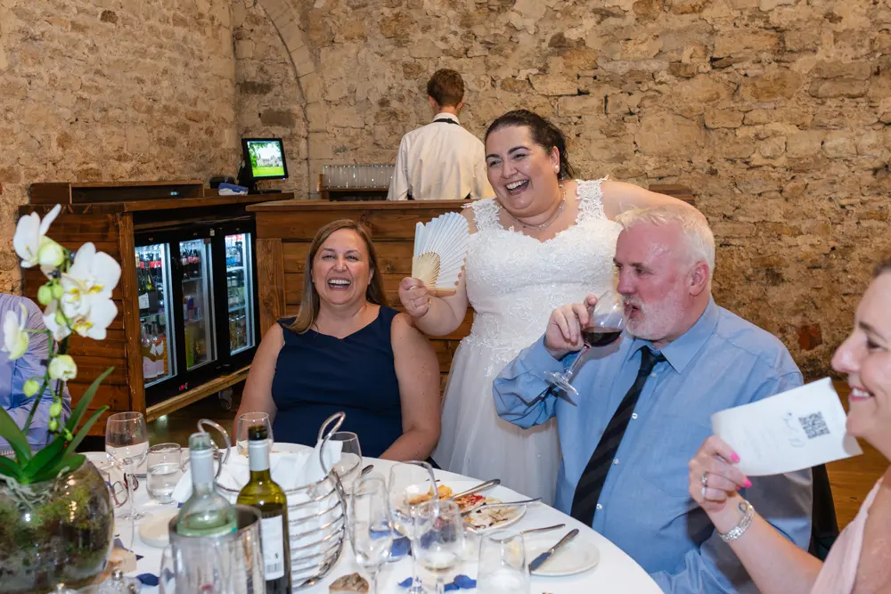 Notley Abbey Wedding photographer. Bride laughing with guests in Monk's refectory.